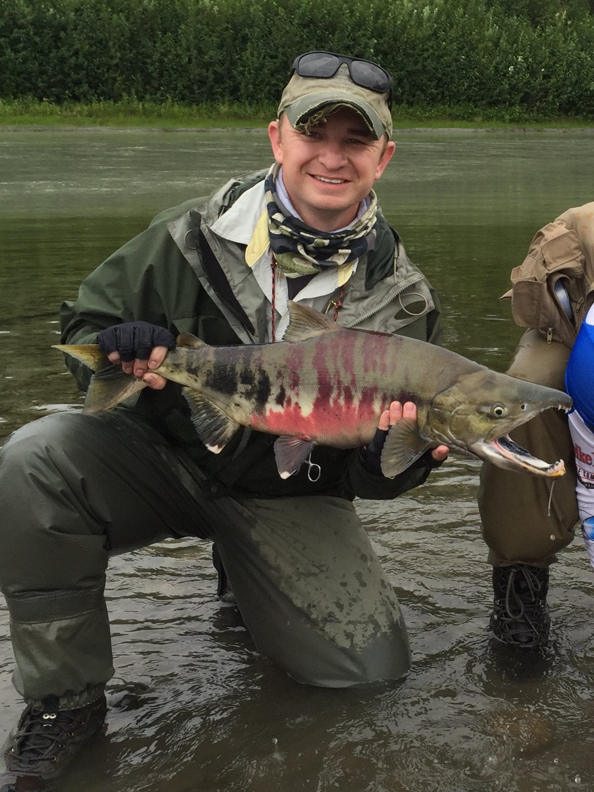 Trevor kneeling in a river holding a large salmon