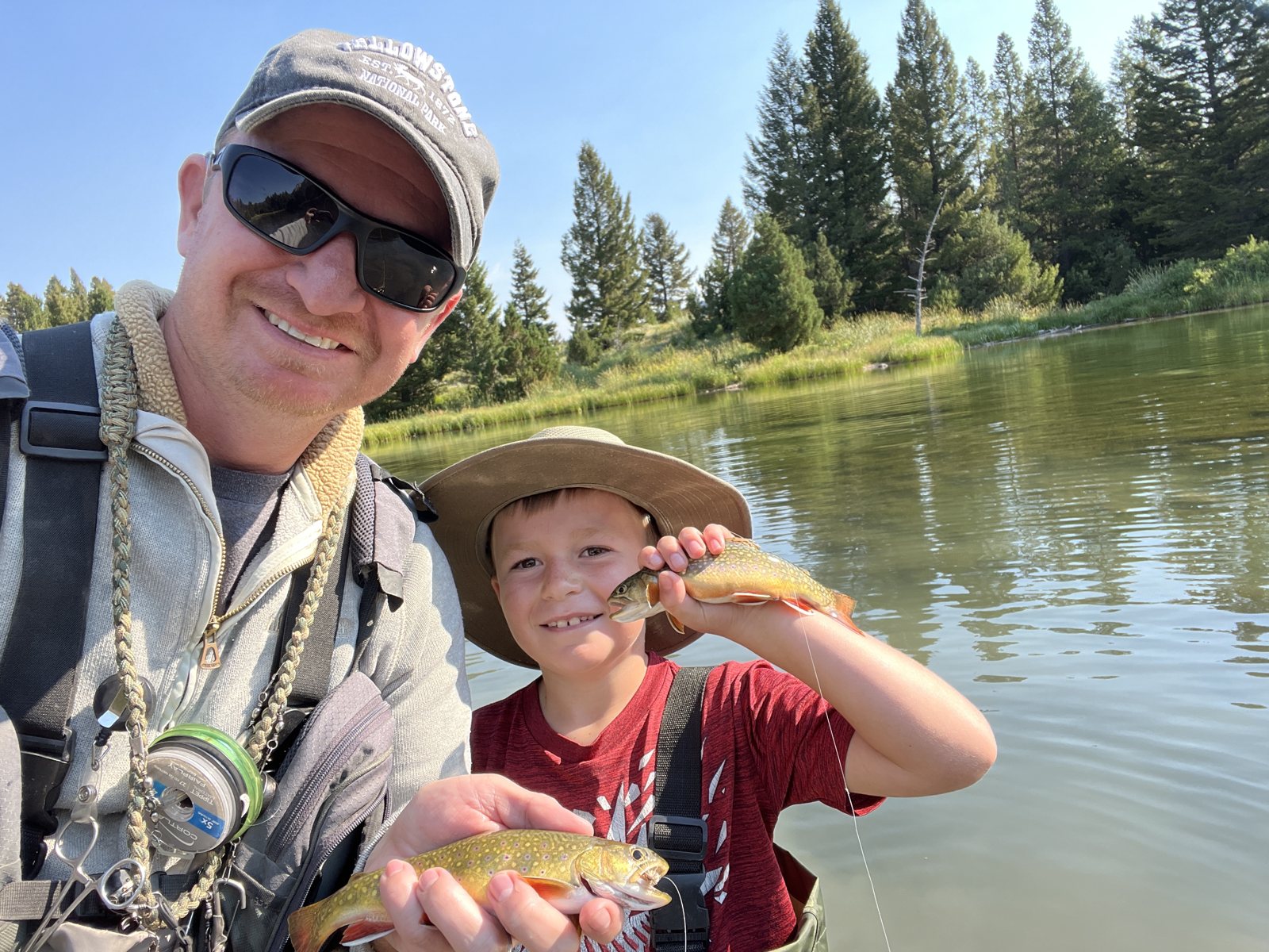 Trevor and Caden each holding a cutthroat trout beside a mountain lake