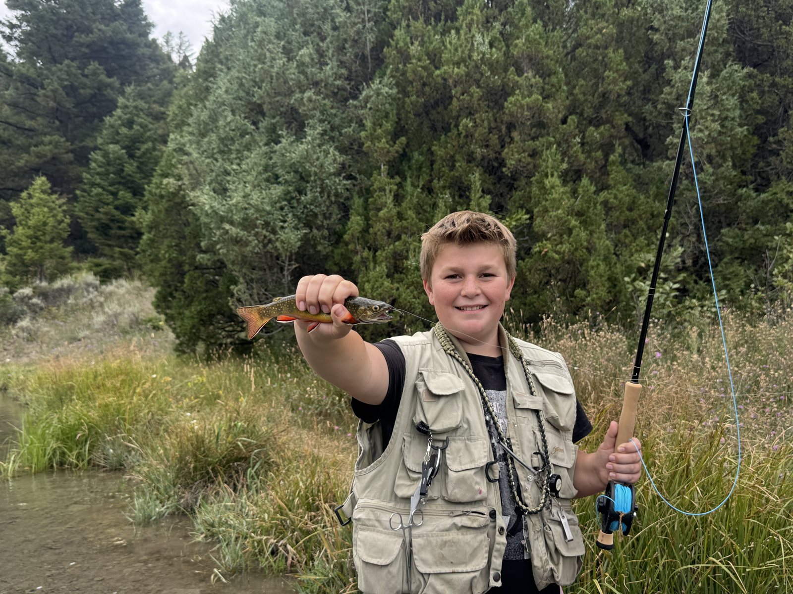 Caden holding a cutthroat trout in a mountain meadow